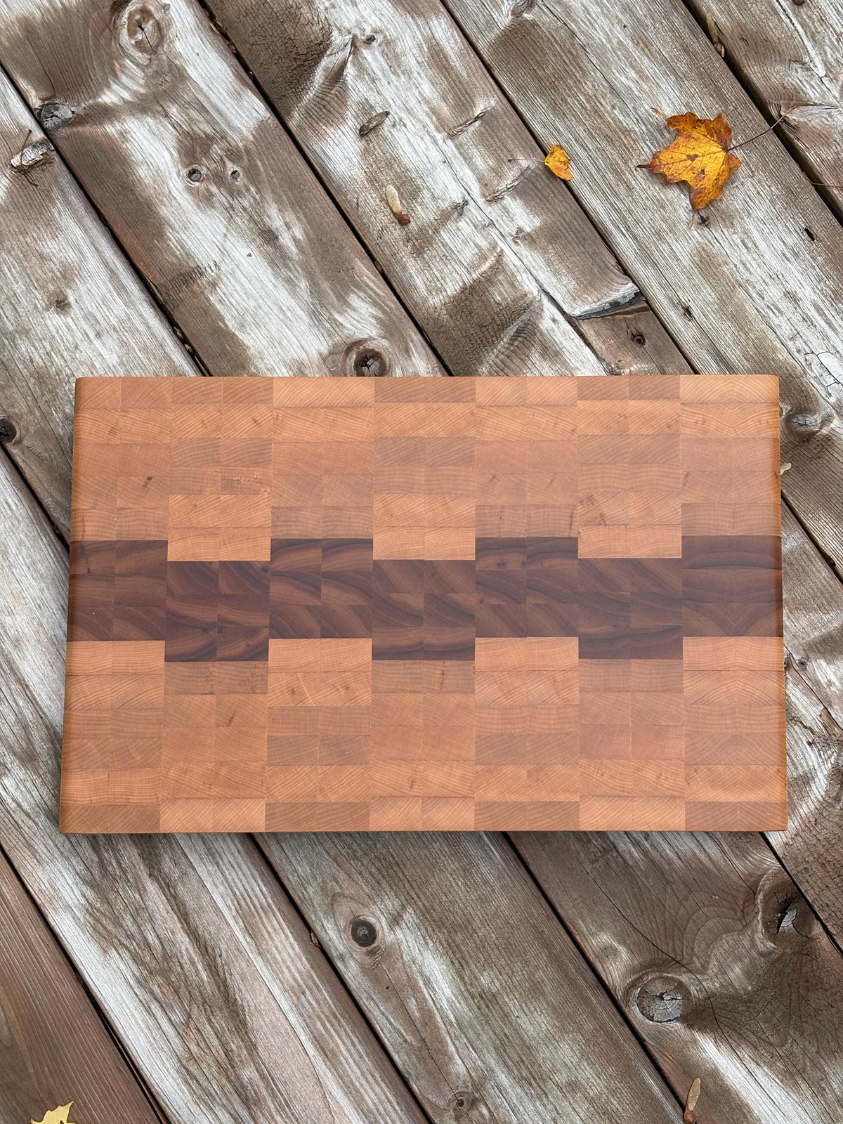 Cherry and maple end grain cutting board 18.5 x 12.75 in on a wood deck, top view