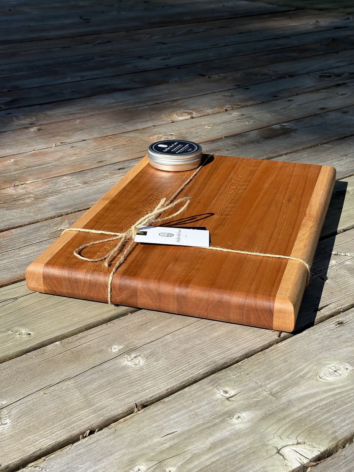 Planche à découper cerisier et érable de 12 x 18 po (vendue), vue en angle de l’autre côté sur une terrasse en bois