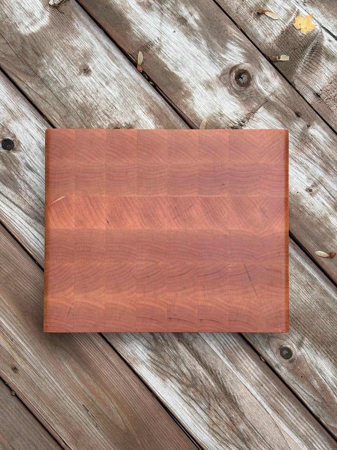 Cherry end grain cutting board 12.75 x 10.5 in on a weathered wood deck, top view