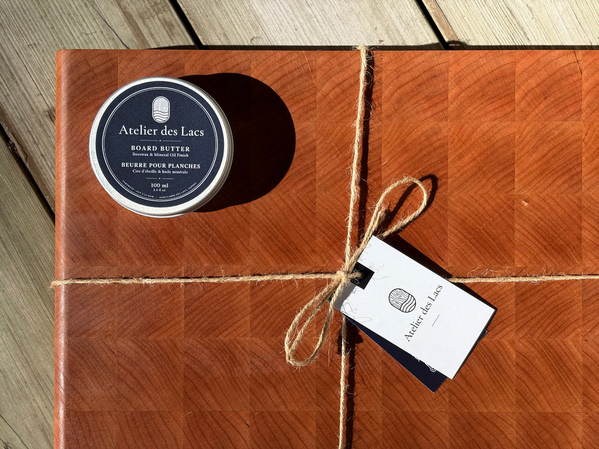 Cherry end grain cutting board 14.5 x 10.5 in tied with twine, with board butter and a gift tag, close-up