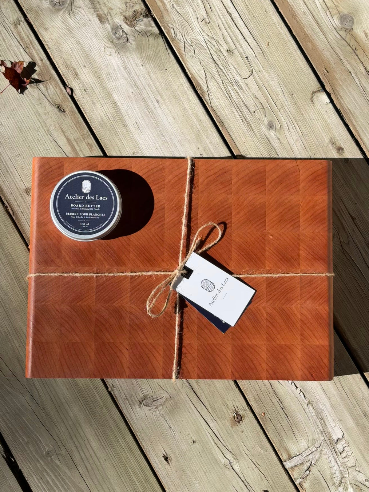 Cherry end grain cutting board 14.5 x 10.5 in tied with twine, with board butter and a gift tag, top view