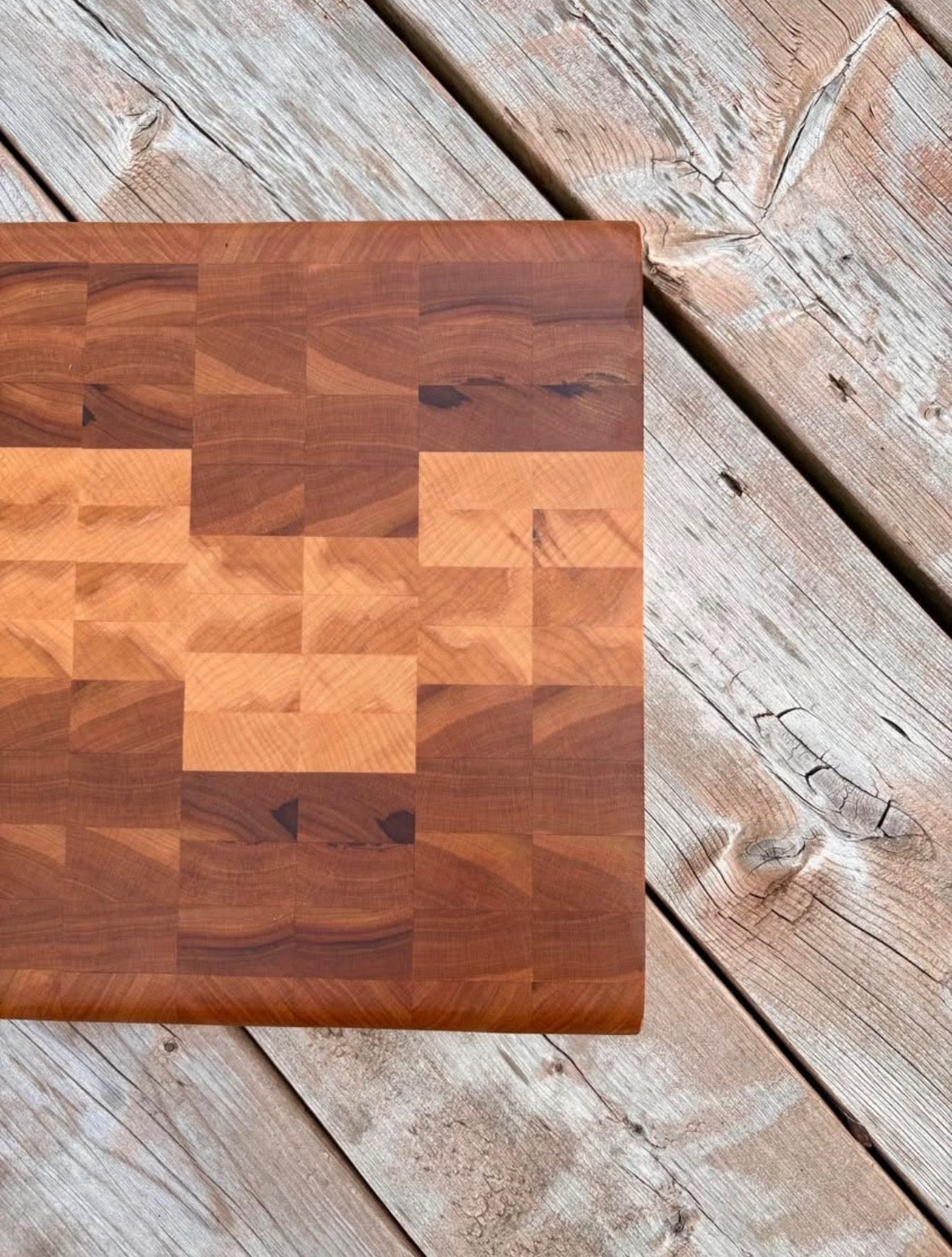 Cherry and maple end grain cutting board 11 x 12 in (sold) on a weathered wood deck, top view