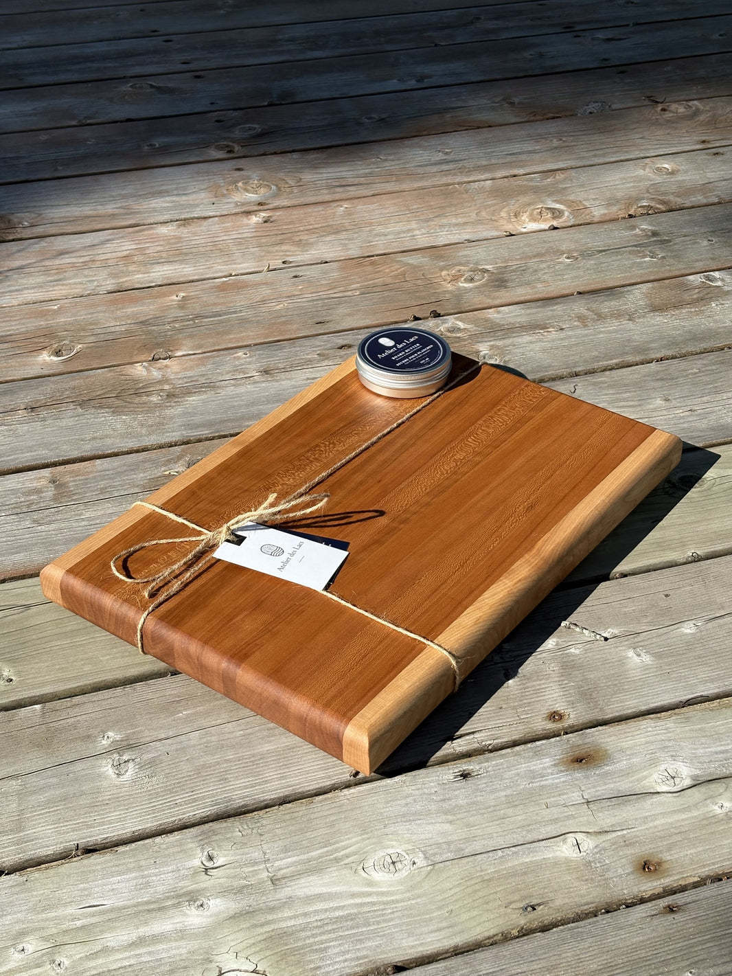 Cherry and maple cutting board 12 x 18 in (sold) with maple edge strips, angled view on a wood deck