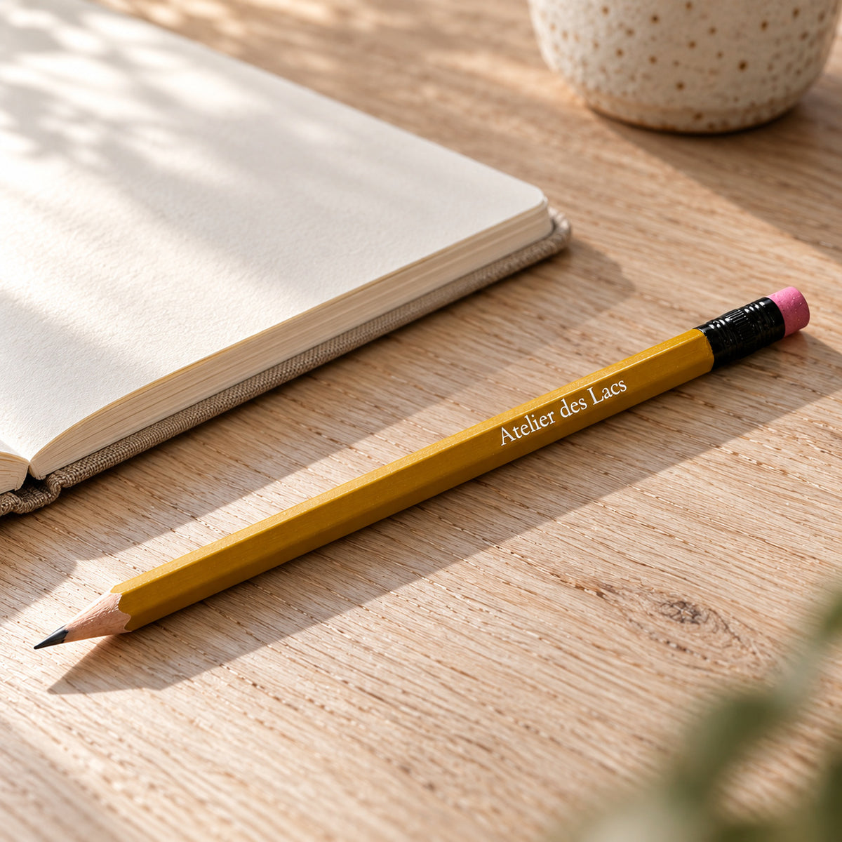 Atelier des Lacs yellow wooden pencil beside an open notebook